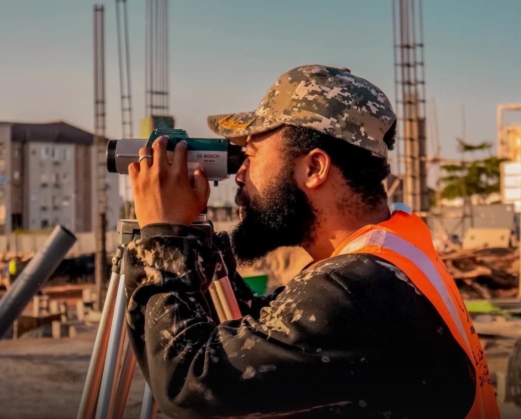 Topógrafo tomando una lectura con nivel de ingeniero en una obra de edificación